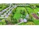 Aerial shot featuring a spacious grassy area, complete with a red barn and outbuildings surrounded by lush trees and houses at 7425 E Thompson Rd, Indianapolis, IN 46239