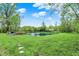 Scenic backyard view with stepping stones to the pond with deck and lush green lawn at 7425 E Thompson Rd, Indianapolis, IN 46239