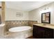 A stylish bathroom featuring a soaking tub, vanity with dark cabinets, and decorative wall art at 7425 E Thompson Rd, Indianapolis, IN 46239