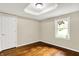 An empty bedroom featuring hardwood floors, a white door and trim, plus a large window at 7425 E Thompson Rd, Indianapolis, IN 46239