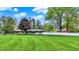 Expansive front yard featuring a one-story home with mature trees and a white fence at 7425 E Thompson Rd, Indianapolis, IN 46239