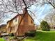 Back of a beautifully maintained home, featuring brick and wood, with a lush green lawn, mature tree, and well-kept landscaping at 7621 Forest Dr, Fishers, IN 46038
