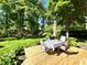 Outdoor table and chairs sit on wooden deck, surrounded by mature trees and landscaping at 7621 Forest Dr, Fishers, IN 46038