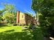 Lush landscaped yard and mature trees surround this brick and vinyl home with red door at 7621 Forest Dr, Fishers, IN 46038