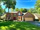 Inviting two-story brick home boasts mature trees, manicured lawn, and red front door at 7621 Forest Dr, Fishers, IN 46038