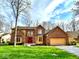 Charming brick home with a well-manicured lawn, mature trees, attached two-car garage and a striking red front door at 7621 Forest Dr, Fishers, IN 46038