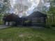 Beautiful log-cabin home featuring a covered porch with an American flag waving in a serene wooded setting at 7916 N Lasalle Rd, Morgantown, IN 46160