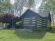 Log cabin-style home with an American flag and a cozy porch surrounded by lush greenery and open lawn at 7916 N Lasalle Rd, Morgantown, IN 46160