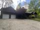Log home with a two-car garage featuring modern doors and a gravel driveway at 7916 N Lasalle Rd, Morgantown, IN 46160