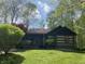 Quaint log cabin with a cozy front porch and American flag waving in the breeze at 7916 N Lasalle Rd, Morgantown, IN 46160