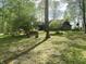Green front yard, with mature trees, a charming log home, and a bench at 7916 N Lasalle Rd, Morgantown, IN 46160