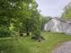 View of home with well maintained lawn and small garden, set amongst mature trees near a pond at 8310 Goat Hollow Rd, Martinsville, IN 46151