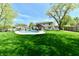 Large backyard featuring a pool, covered patio area, green grass, mature trees, and a privacy fence at 8548 Scarsdale W Dr, Indianapolis, IN 46256