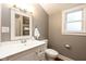A well-lit bathroom with a vanity, toilet, and window, offering a clean and functional space at 940 E Pleasant Run Parkway North Dr, Indianapolis, IN 46203