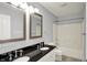 Well-lit bathroom with double sinks, black countertops, and a combined shower and bathtub at 9583 Greenthread Dr, Zionsville, IN 46077