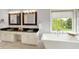 Elegant bathroom featuring double vanities with black countertops and a soaking tub at 9583 Greenthread Dr, Zionsville, IN 46077