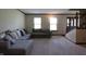 Spacious living room with comfortable gray couch, carpeted floor, and natural light from two windows at 9903 E Raymond St, Indianapolis, IN 46239