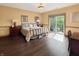 A bedroom with hardwood floors, tan walls, a king bed, and sliding doors to a balcony at 1026 Jackson St, Columbus, IN 47201