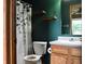 Bathroom with green walls, wood shelves, white toilet, sink, vanity and a decorative shower curtain at 107 Camelia Ct, Mooresville, IN 46158