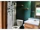 Bathroom with green walls, wood shelves, white toilet, sink, vanity and a decorative shower curtain at 107 Camelia Ct, Mooresville, IN 46158