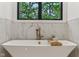 Close up of soaking tub with gold fixtures, marble backsplash and window view at 11064 Hamilton Run, Zionsville, IN 46077