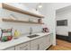 Butler pantry features white countertops, a stainless sink, and open wood shelves for décor and storage at 11064 Hamilton Run, Zionsville, IN 46077