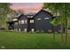 A home's back exterior features dark siding with an outdoor deck and landscaped yard at 11064 Hamilton Run, Zionsville, IN 46077
