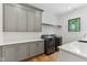 Bright laundry room with sleek gray cabinets, white countertops, and modern black washer and dryer at 11064 Hamilton Run, Zionsville, IN 46077