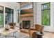 Cozy living room featuring a stone fireplace, hardwood floors, large windows, and comfortable armchairs at 11064 Hamilton Run, Zionsville, IN 46077