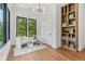 Bright sitting room featuring a modern chandelier, beautiful hardwood floors, and a custom built-in bookcase at 11064 Hamilton Run, Zionsville, IN 46077