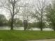 Scenic backyard view with a serene pond surrounded by lush greenery and mature trees at 117 Fountain Lake Dr, Greenfield, IN 46140