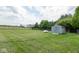 Large backyard featuring lush green grass, a storage shed, trees, and fencing at 1683 W County Road 300 S, Danville, IN 46122