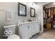 Well-lit bathroom with double sinks, marble counters, mirrors and adjacent walk-in closet at 1808 E 11Th St, Indianapolis, IN 46201