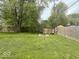 Spacious backyard with lush green lawn, mature trees, and stone fire pit for outdoor enjoyment at 212 Vasbinder Dr, Chesterfield, IN 46017