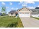 Tan home showcasing a blue front door, a two-car garage and a freshly landscaped yard at 2334 Black Rock Cir, Lebanon, IN 46052