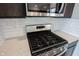 Close up of gas range with white quartz countertops and subway tile backsplash in updated kitchen at 2628 Lamar Dr, Whitestown, IN 46075