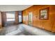 An unfinished living room with wood paneled walls and an open doorway at 268 S Grant Ave, Indianapolis, IN 46201