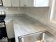 Close-up of the kitchen's granite countertops, stainless steel sink, and white subway tile at 2924 Main St, Anderson, IN 46016
