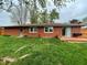 Back exterior view of a brick home with a small wooden deck and a lush green lawn at 2935 Flintwood Dr, Columbus, IN 47203