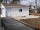 Side view of detached garage with white door, siding, and concrete driveway at 3008 W Grace Ln, Muncie, IN 47304