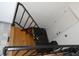 View looking down on wooden stairs with black metal railings contrasting with black tile and a white door at 3426 Ireland Dr, Indianapolis, IN 46235