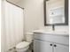 Clean bathroom featuring a shower with curtain, toilet, gray vanity with black hardware, and a modern rectangular mirror at 401 Jersey St, Westfield, IN 46074