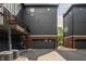 Townhome exterior featuring black siding, brick accents, garage, and balcony with string lights, with a glimpse of greenery in the background at 401 Jersey St, Westfield, IN 46074