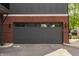 Close-up of a gray garage door with horizontal panels, flanked by brickwork and exterior lighting, set against a gravel landscape at 401 Jersey St, Westfield, IN 46074