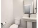 A modern powder room features a pedestal sink, black hardware, and crisp white walls at 401 Jersey St, Westfield, IN 46074