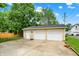 Two-car detached garage with concrete driveway, white doors, and tan siding, providing parking and storage space at 410 E North St, Greenfield, IN 46140