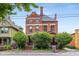A stately brick home with mature trees, showcasing classic architecture under a clear sky at 419 N College Ave, Indianapolis, IN 46202
