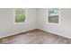 Cozy bedroom with wood-look flooring, two windows providing natural light, and neutral wall paint at 4432 Brittany Rd, Indianapolis, IN 46222