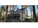 View of the house exterior with a large deck and a two-car garage nestled among mature trees in the fall at 448 Tamarack Ln, Noblesville, IN 46062