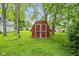 Charming red storage shed nestled among mature trees in the backyard, providing ample storage at 4510 Gadsden St, Indianapolis, IN 46241